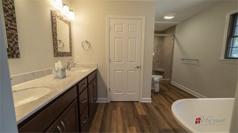Bathroom with luxury vinyl planks, double bowl vanity, cultured marble vanity top, tiled shower, corner bench