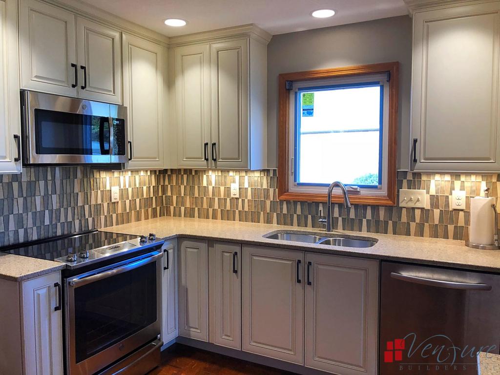 Kitchen remodel, Antique white raised panel cabinets with chocolate glazing, quartz countertops, glass tile backsplash, stainless steel appliances, hardwood flooring, pull down sink faucet, oiled rubbed bronze hardware, double equal under-mount kitchen sink
